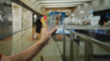 Kapalı bir alışveriş merkezinde el ele tutuşan İsviçre frankı banknotları. Bulanık pazar geçmişi olan bir adam tarafından sergilenen alışveriş ve para değişimi..