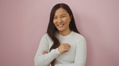 Çinli bir kadın pembe bir arka plan önünde özgüvenle gülümsüyor güzellik ve pozitiflik sergiliyor..