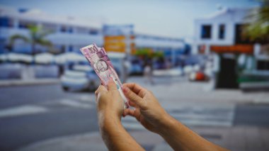 Bir şehir caddesinde Filipinli pezoları tutan adamın elleri, hareketli bir şehir ortamında yatırım, finans ve iş kavramlarını ön plana çıkarıyor..