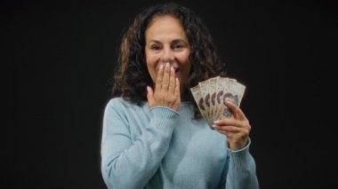 Meksika banknotları tutan orta yaşlı bir kadın izole edilmiş siyah arka planda şaşırmış bir ifade var..