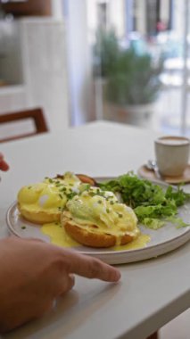 Sıcak bir restoran ortamında yumurta ve kahve servisi yapan eller lezzetli bir kahvaltı ve hoş bir ev yemeği deneyimini ön plana çıkarıyor..