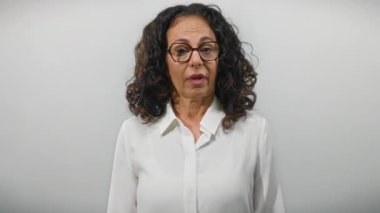 Kıvırcık saçlı ve gözlüklü olgun bir kadın soyutlanmış beyaz arka planda dışa dönük ve zarif