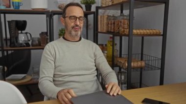 Adam rahat bir iş yerinde raflar ve mutfak eşyalarıyla rahatlamış ve olgun bir atmosfer yayıyor..