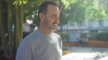 İspanyol çift, yeşil alanlarla çevrili bir şehir parkında sevgi dolu bir anı paylaşıyor. Şehir güneşinin altındaki bağlarını ve neşelerini vurguluyorlar..