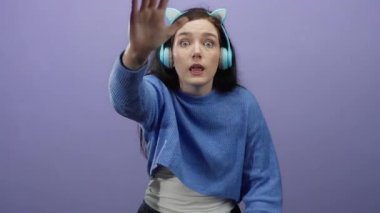 Mor bir arka plana karşı kulaklıkla bağıran ve el kol hareketi yapan bir kadın yoğun duygu ve iletişimdeki bağlılığı resmediyor.