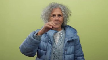 Sarı duvara yaslanmış mavi ceketli, dışlanmış arka planda anlamlı bir yüz ifadesi olan iyi niyetli bir kadın..