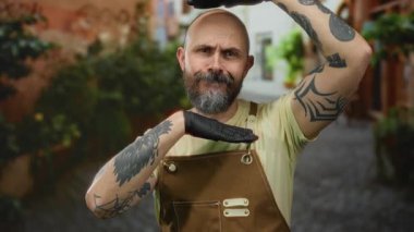 Tulum ve eldiven takmış sakallı kel bir adam tuhaf bir şehir caddesinde yaratıcı bir şekilde poz veriyor..