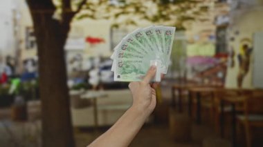 Şehir kafeteryasının arka planı bulanık bir terasında elinde Singapur dolarları tutan bir adam..