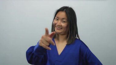 Mavi tişörtlü kadın gülümsüyor ve beyaz arka plana işaret ediyor olumlu duyguları ifade eden izole bir duvar.