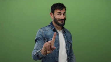 Sakallı İspanyol adam yeşil arka planda parmak hareketi yapmıyor..