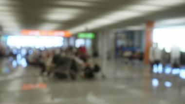Parlak tabela ve modern mimari detaylarla çevrili arka planda bulanık gezginlerle kapalı hava alanı görüntüsü