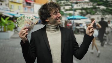 Arjantinli adamın elinde peso banknotlar var, gülümsüyor ve işaret ediyor, kentsel enerjiyi finansal görüntülerle harmanlıyor..