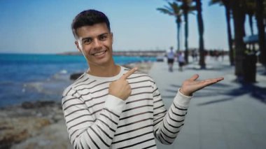 Genç adam deniz kenarındaki gezinti alanında güneşli gökyüzünün altında rahatlık ve rahatlığın esansını yakalıyor..