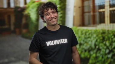 Akdeniz 'de gönüllü tişört giyen İspanyol bir adam yeşil arka planda toplum ruhunu ve dostluğunu sergiliyor.