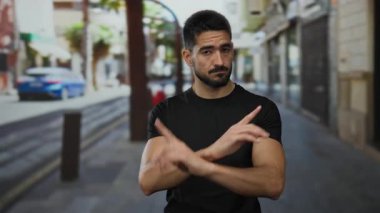 Yakışıklı İspanyol genç bir adam, şehir sokaklarında eğlenirken ve etkileşim kurarken, canlı bir şehir zeminine karşı gelişigüzel giyinmiş, siyahlar içinde..