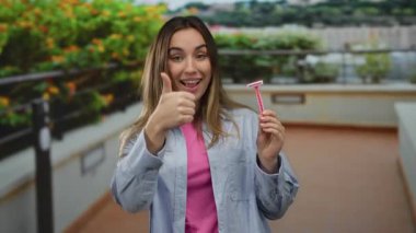 Gülümseyen, elinde pembe jiletle gezen, açık hava parkı ortamında başparmak kaldıran, günlük kıyafetler giyen, yemyeşil bir kadın, onay ve memnuniyet öneriyor..