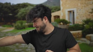 Sakallı genç adam yemyeşil bir parkta hayali bir halat çekiyor güneşli bir günde açık hava oyununun taklidini yapıyor..