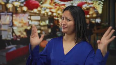 Şehir sokaklarında renkli ışıklarla dolup taşan pazarda mavi gömlekli bir kadın Çin kültürünün unsurlarını ve canlı pazar atmosferini ön plana çıkarıyor..