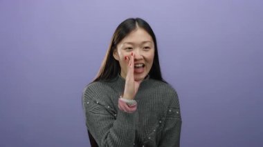 İzole edilmiş mor arka planda bağıran, gri bir kazak giyen, uzun siyah saçlı, canlı kırmızı tırnaklı, Asyalı yetişkin, kadın, çekici bir kadın..