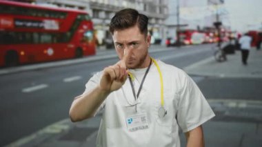 Sakallı genç doktor, şehrin arka planında kırmızı çift katlı otobüsleri gösteriyor, steteskop takıyor, sağlık bilincini veya tıbbi konsepti resmediyor..