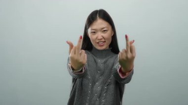 Beyaz arka planda kaba bir jest yapan bir kadın meydan okuduğunu ve neşeli bir ifadeyle gündelik kıyafetlerini giydiğini ifade ediyor..