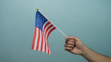 Mavi arka planda Amerikan bayrağını tutan adam vatanseverliği ve milli gururu simgeliyor..