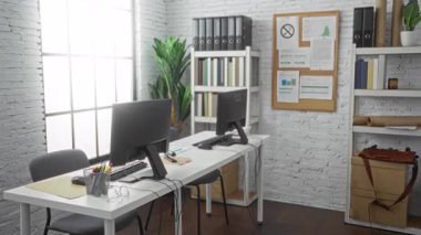 Modern ofis ortamında el sıkışan iki kadın, profesyonel bir ortamda bilgisayar ve ofis malzemelerinin yanında takım çalışması ve işbirliği sergiliyorlar..