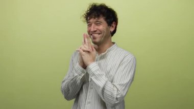 İspanyol bir adam, neşeli bir parmak tabancası hareketi yapıyor. Parlak sarı bir arkaplan üzerinde neşeli bir yüz ifadesi ve sıradan çizgili bir tişörtle eğlenceli ve yaratıcı bir sahne öneriyor..