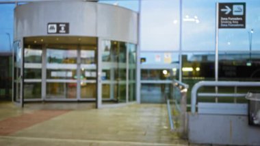 Açık hava havaalanı girişinin bulanık görüntüsü dairesel bir kapı ve tabela, gelip geçici ve hareketli bir atmosfer taşıması.