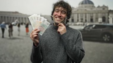 İspanyol adam, elinde Czech Koruna banknotlarıyla Vatikan 'ın St. Peter Meydanı' nda gülümseyerek kültürel zıtlık ve açık hava zenginliğini yakalıyor..