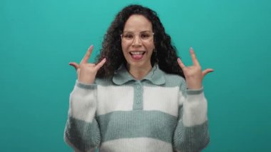 Latin kökenli genç bir kadın yeşil duvarlara dil uzatarak hareketler yapıyor..