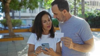 Şehir parkında yaşayan orta yaşlı İspanyol bir çift banka kartını hevesle inceliyor, açık havada bir şehirde aşkı ve bağlantıyı vurguluyor..