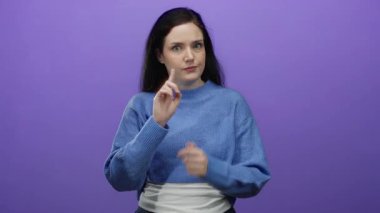 Esmer, mavi kazaklı bir kadın canlı mor bir arkaplan karşısında el hareketleri ve yüz ifadeleriyle çeşitli duygular ifade ediyor..