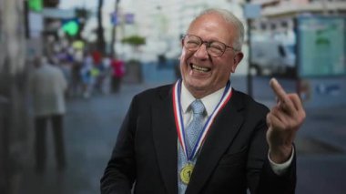 Madalya takmış kıdemli bir adam kalabalık bir sokakta kaba bir jest yapıyor. Açık bir şehir ortamında zıt duygular sergiliyor. Bir mizah anını yakalıyor ve sürpriz yapıyor..