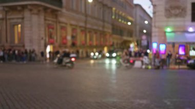 Roma 'nın eski kasabasında bulanık bir gece sahnesi. Sokakta insanlar ve araçlar sokak lambaları ve renkli işaretler altında..