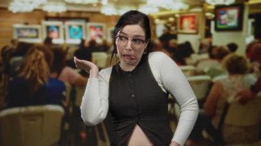 Sanat galerisindeki gözlüklü kadın, kalabalığın duvarlarda canlı sanat eserlerini gözlemlerken komik suratlar yapıyor..