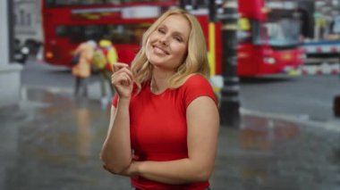 Kırmızı kalbi tutan kadın, arka planda aşk ve mutluluğu temsil eden ikonik çift katlı otobüsüyle şehir caddesinde neşeyle gülümsüyor..