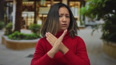 Dışarıda duran kırmızı kazaklı kadın şehir sokaklarında eli silahlı X işareti yapıyor. Bu da geçmişinde bulanıklık olan ya dur ya da reddi simgeliyor..