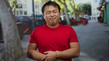 Şehirdeki sokak ortamında midesini tutan kırmızı gömlekli bir adam bulanık bir şehir geçmişine karşı rahatsızlığını dile getiriyor..