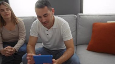 Çift, rahat bir apartman dairesinde, birlikte ve iletişimi gösteren bir tablette video görüşmesinin tadını çıkarıyor..