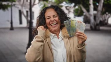 Bir şehir caddesinde neşeli bir ifadeyle neşe içinde Romanya banknotları tutan bir kadın, açık havada başarı ve mutluluk duygusunu somutlaştırıyor..