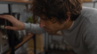 Genç adam mikrodalgayı ofis mutfağının iç düzeninde ayarlıyor, elle tuşlara odaklanıyor, modern iş çevresi aletlerini gösteriyor..