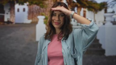 Pembe gömlek ve kot ceket giyen kadın, şehir caddesinde güneş gözlüğü, bulanık binalar, canlı şehir manzarasında neşeli şehir havası..