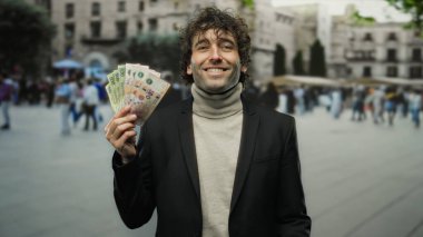 Kalabalık bir caddede elinde Arjantin pezosu tutarken gülümseyen İspanyol adam..