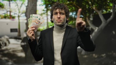 Arjantinli pesoları elinde tutan İspanyol bir adam, şehir caddesinde dikiliyor, kendine güvenen bir finansal durumu ima ediyor..