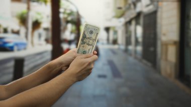 Şehir sokaklarında elinde Amerikan doları banknotuyla gezen adam ekonomi ve finans odaklı şehir bağlamında para gösteriyor..