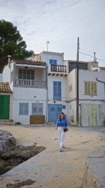 Mallorca kıyısında Akdeniz mimarisi olan, arka planda büyüleyici binalar olan, tarihin ve manzaranın bir karışımını yakalayan bir kadın eski şehirde yürüyor..