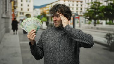 Adam bir şehir caddesinde bir avuç Rus rublesini tutarken stresli görünüyor. Bir anlık finansal tefekkür yakalıyor..