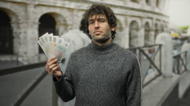 Elinde Czech Koruna banknotları tutan adam Roma 'daki ikonik kolezyumun yanında duruyor. Açık hava şehrinde eşsiz bir kültürel karışım yakalıyor..