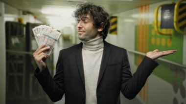 Teknedeki İspanyol adam Suudi riyal banknotlarını elinde tutuyor, deniz kenarında bir arka planda, zenginlik ve seyahat hissi yaratıyor..